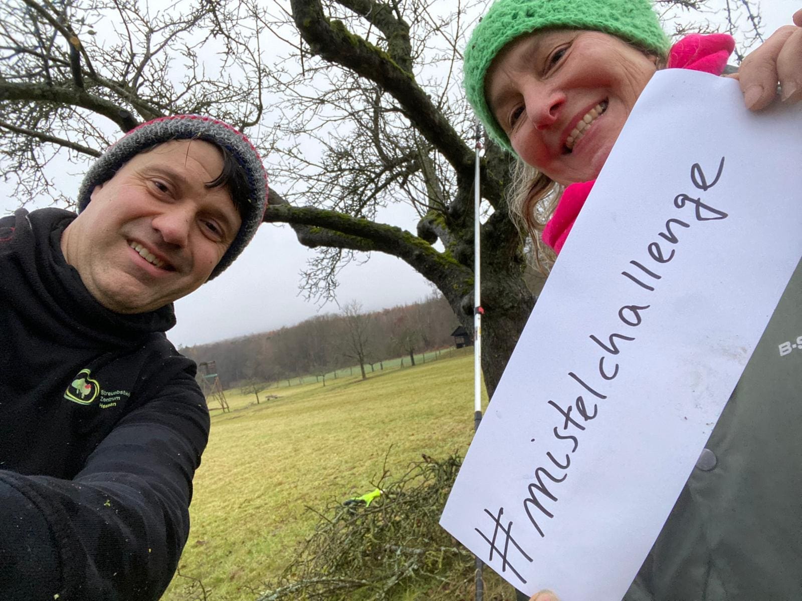 Zwei Personen halten ein Schild hoch mit #mistelchallenge